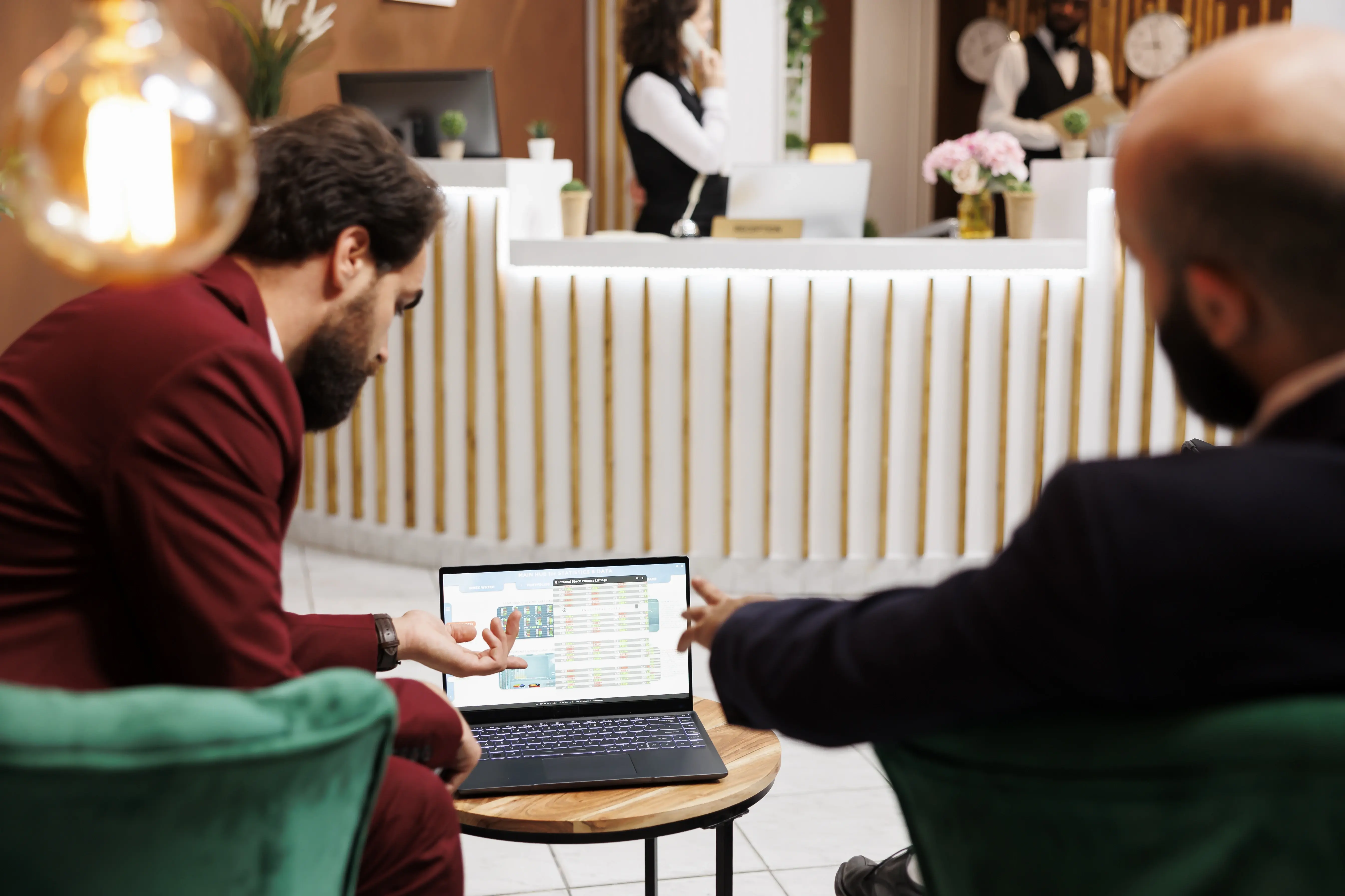 Event planners reviewing venue layouts on a laptop during a meeting inside a hotel reception area